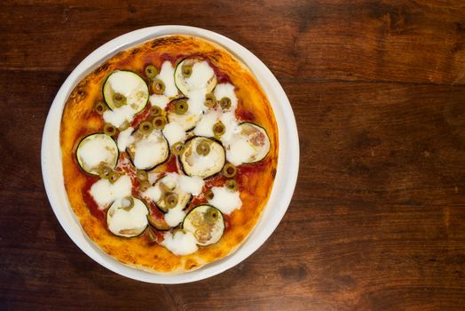 Italian pizza with zucchini, eggplant and green olives seen from above