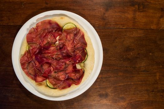 Italian pizza with bresaola, zucchini and eggplant seen from above