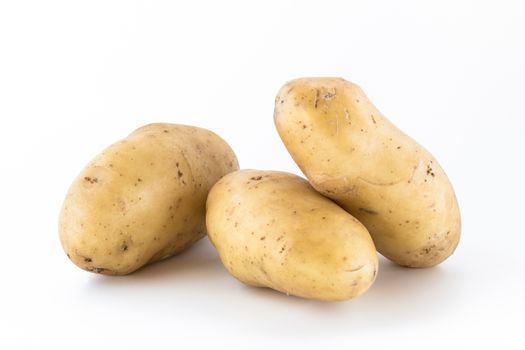 Three raw potatoes, unpeeled, isolated on white background.