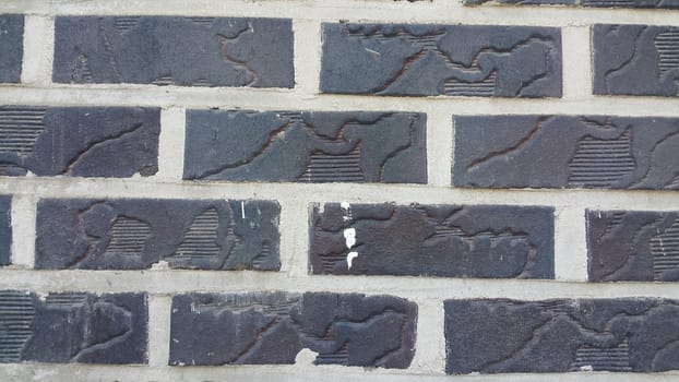 Closeup texture of black brick wall. A background of a weathered old exterior brick wall in the sunshine.