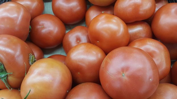 Red tomatoes in red basket in market for sale. A fruit background for text and advertisements