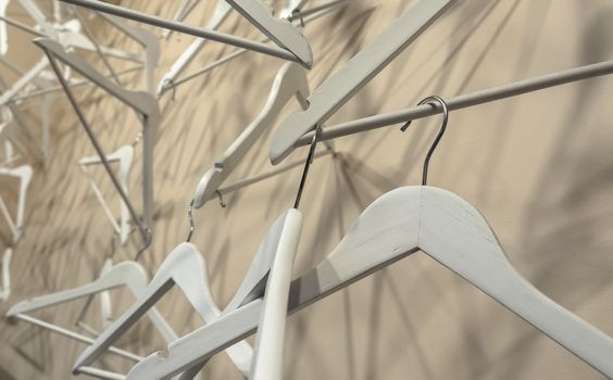 Empty wooden clothes hangers casting deep shadows. Real coat hanger wood pattern. Abstract fashion concept.