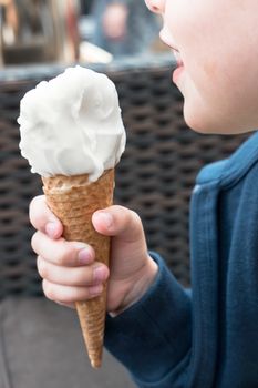 Portrait of a little girl who eats sitting ice cream. Defocused blurry background.