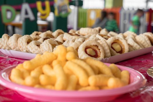 Party snacks - potato chips in pink dish and mini pizzas. Ready to be eaten. Traditional italian plate for party, birthday and every event. Selected focus