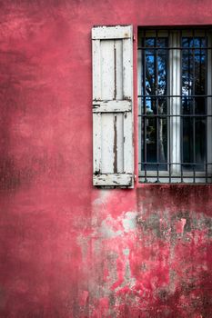 Decorative grungy window on an old red stucco wall