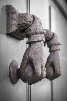 Rusty hand shaped knocker in an old door. Defocused blurry background.