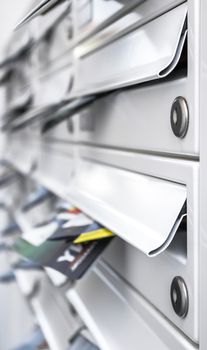 Modern metal mail boxes, full of leaflets. Ideal for concepts. Shallow depth of field.