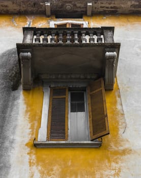 Ancient Italian facade with peeling plaster, near the window and balcony.