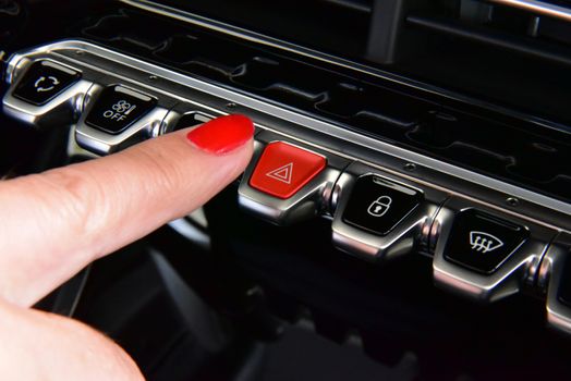 Female finger hitting car emergency light botton