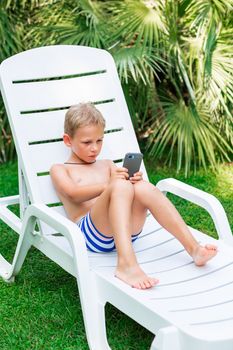 Boy playing games on the telephone. Gadget dependency disorder problem for kids during holiday vacation at the seaside concept