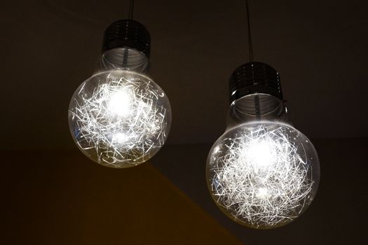 two burning chandeliers in the form of ordinary bulbs on the ceiling.