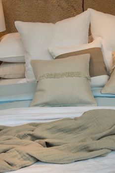 Close up well made bed with pastel color pillows and bedspread, high angle view
