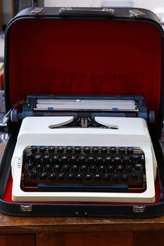 Close up one old portable desk typewriter with Latin alphabet keyboard in open leather case on table, high angle view