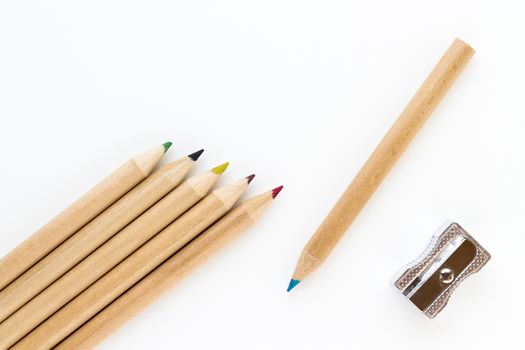 Group of crayons and pencil sharpener on white background and seen from above.