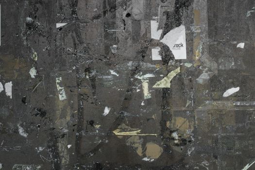 Empty notice board of dark metal, covered with remnants of tape torn.