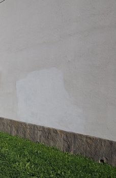 plaster wall with stone tiles and grass useful as a background