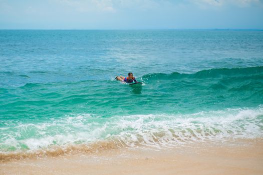 Sexy slim girl riding on surf board in the ocean. Healthy active lifestyle in summer vocation