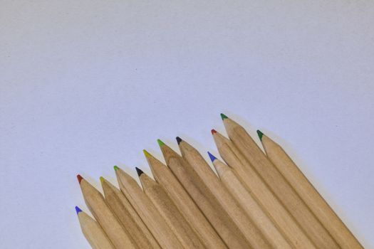 colored crayons lined up on a white sheet, horizontal image