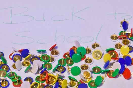 thumbtacks scattered on a white paper with the words "back to school", horizontal image