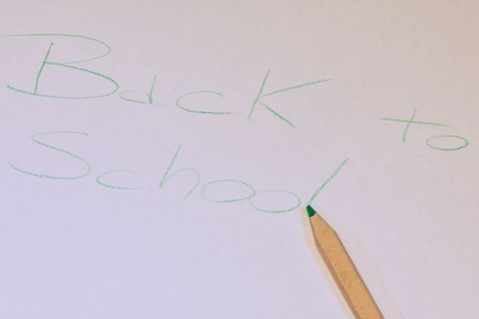 Written "back to school" made with a colored pencil on white paper, horizontal image