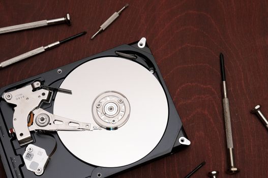 Recover a failed hard drive with a screwdriver.Internal parts of a hard disk on an isolated braun,wood background.