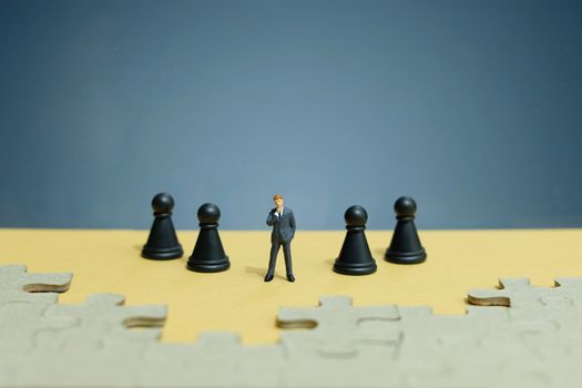 Business strategy conceptual photo - Miniature of businessman standing in the middle on chess army line with jigsaw puzzle