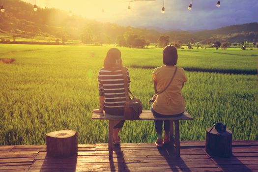 Two traveller enjoying a looking at sunset on rice field