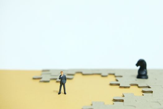 Conceptual photos of business strategies - miniature people businessmen standing in front of uncomplete jigsaw puzzles