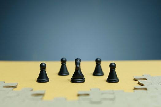 Conceptual photo of business strategy - a line of horse chess pieces in the middle of an army and jigsaw puzzles