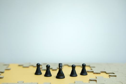 Conceptual photo of business strategy - a line of horse chess pieces in the middle of an army and jigsaw puzzles