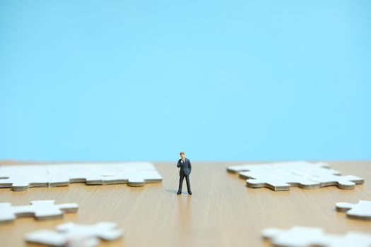 Conceptual photos of business strategies - miniature people businessmen standing in front of uncomplete jigsaw puzzles