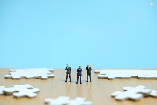 Conceptual photos of business strategies - miniature people businessmen standing in front of uncomplete jigsaw puzzles