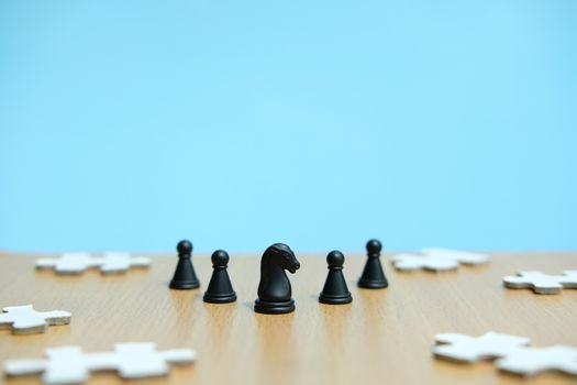 Conceptual photo of business strategy - a line of horse chess pieces in the middle of an army and jigsaw puzzles