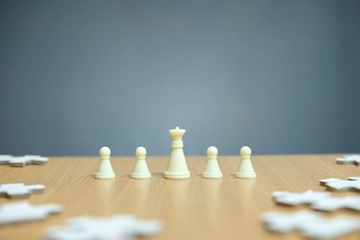 Conceptual photo of business strategy - a line of king chess pieces in the middle of an army and jigsaw puzzles