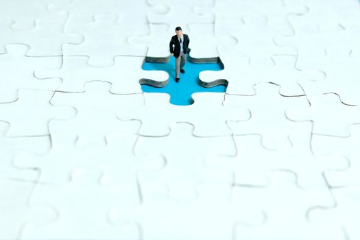 Business strategy conceptual photo - miniature businessman walking inside missing piece of puzzle