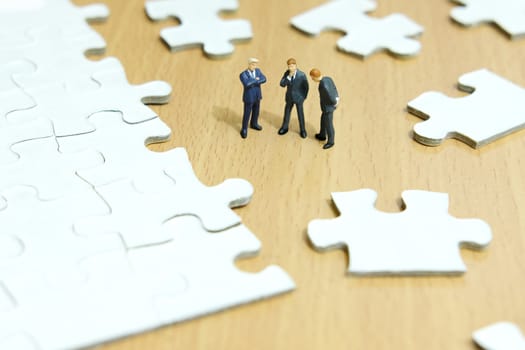 Business strategy conceptual photo - Group of miniature businessman have a discuss above puzzle jigsaw