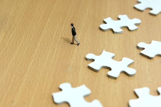 Business strategy conceptual photo - miniature businessman walking in front of missing piece puzzle