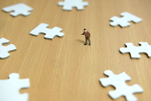 Business strategy conceptual photo - miniature businessman pointing on missing piece puzzle