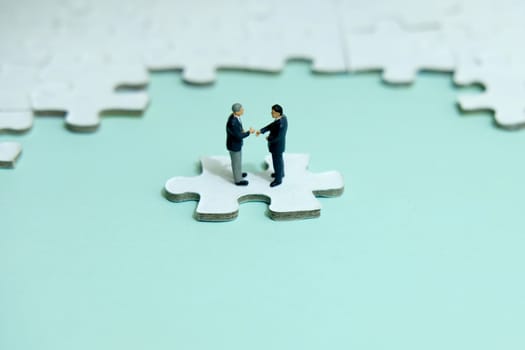 Business strategy conceptual photo - Miniature businessman make contract agreement above jigsaw puzzle