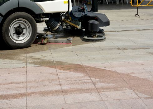 urban sweeper cleans road from dirt with a round brush

