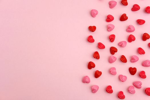 Red and pink heart beads shape, top view flat lay with pink background. Love and romance conceptual object