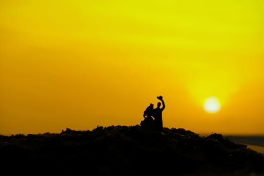 miniature people / toy photography - conceptual valentine holiday illustration. A Couple silhouette walking at the sand beach