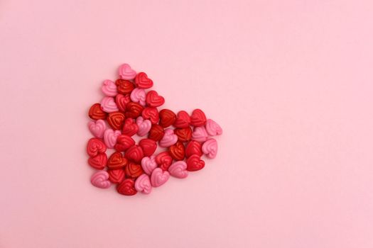 Red and pink heart beads shape, top view flat lay with pink background. Love and romance conceptual object