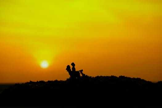 miniature people / toy photography - conceptual valentine holiday illustration. A couple silhouette riding a scooter at the sand beach