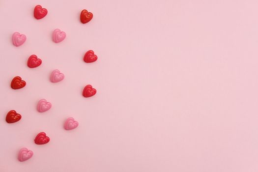 Red and pink heart beads shape, top view flat lay with pink background. Love and romance conceptual object