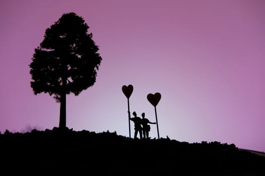 miniature people / toy photography - conceptual valentine holiday illustration. A Couple silhouette standing at the hill holding heart balloon