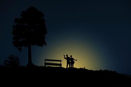 miniature people / toy photography - conceptual valentine holiday illustration. A happy couple silhouette standing at the hill enjoying moon light