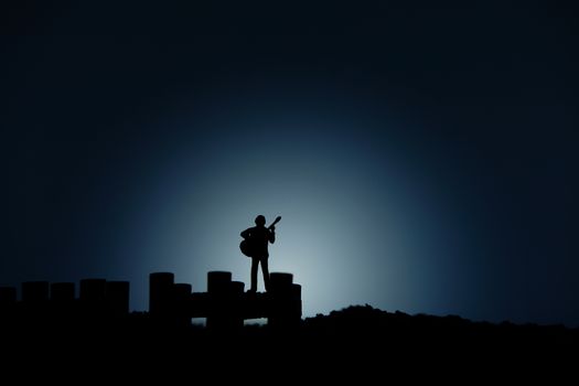 miniature people / toy photography - conceptual valentine holiday illustration. A man singing with guitar at the edge of bridge under moon light on river