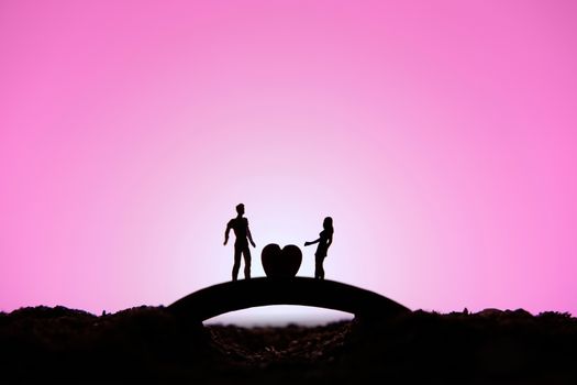 miniature people / toy photography - conceptual valentine holiday illustration. A man proposing a girl silhouette above the bridge