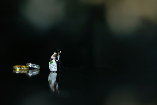 Miniature wedding concept. Bride and groom walking in front of their wedding ring. image photo